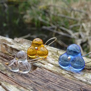 Glasperlen, drei Ohrringe aus Glas in braun, Blau und klar,silber, auf Holz