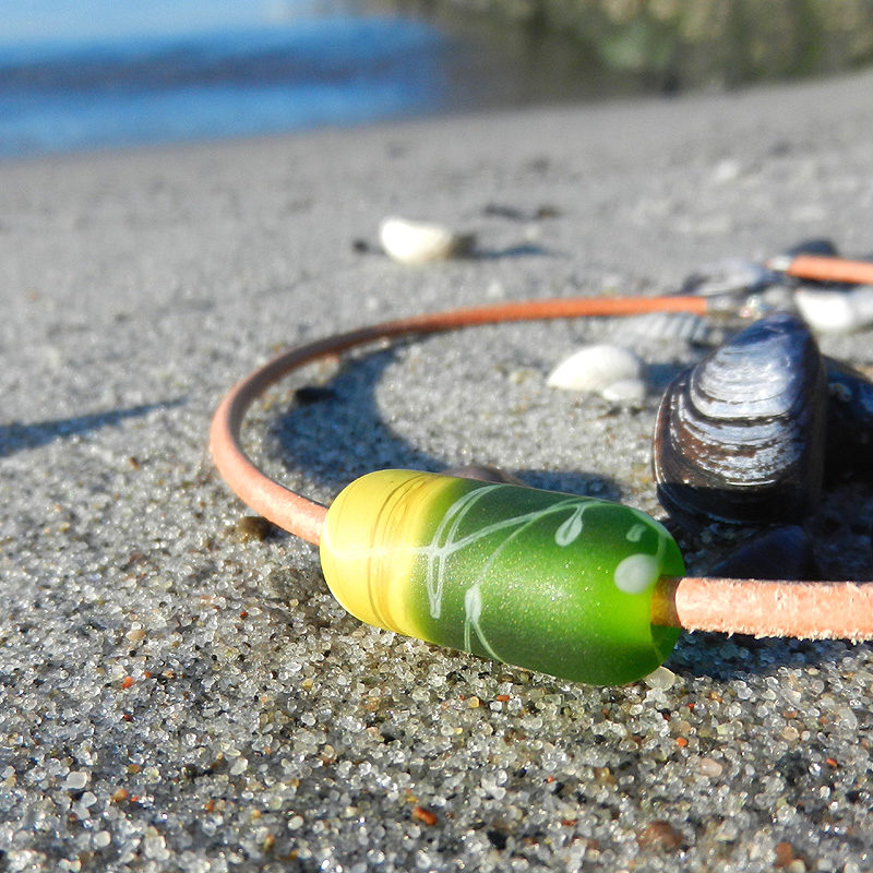 Einzelne Glasperle in Walzenform, handgefertigtes Unikat von schmuckes Glas. Glasperle in zwei Grün-tönen. Hellbraunes Lederband.